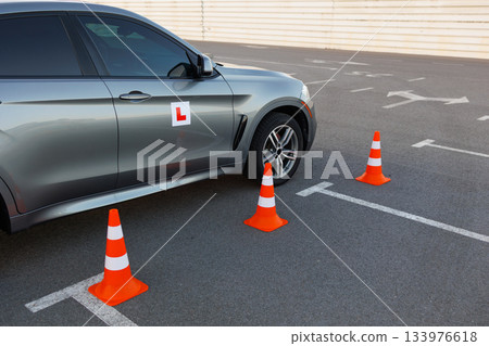 Driving School Car by Traffic Cones on Marked Parking Lot Driving School Car by Traffic Cones on Marked Parking Lot 133976618