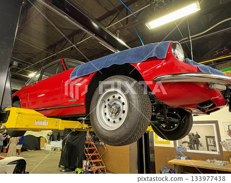 Classic Red Car on a Lift in a Workshop Ready for Restoration 133977438