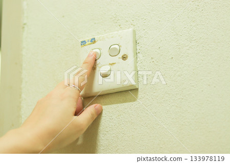 女人的手在操作一個老式電開關 女人的手在操作一個老式電開關 133978119