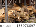 Wood is stacked in a storage area close to a building, ready for use in fireplaces or grills when the temperature drops 133978697