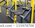 Heavy-duty workout structure sits empty in a park. Grass and pathways surround the equipment. Ideal for strength training activities 133978706