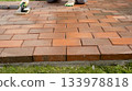 Worker cleaning new brick paver patio surface 133978818
