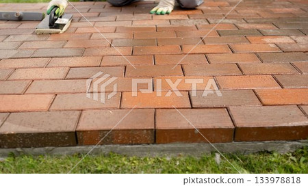 Worker cleaning new brick paver patio surface 133978818