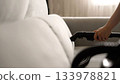 Hand using steam cleaner cleaning sofa upholstery 133978821