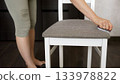 Woman cleaning chair seat with vacuum cleaner brush 133978822