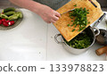 Person chopping fresh green onions in kitchen 133978823