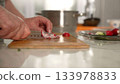 Chef slicing fresh radishes on wooden cutting board 133978833