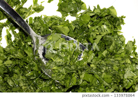 Close up of chopped coriander and parsley herbs on a white background Close up of chopped coriander and parsley herbs on a white background 133978864