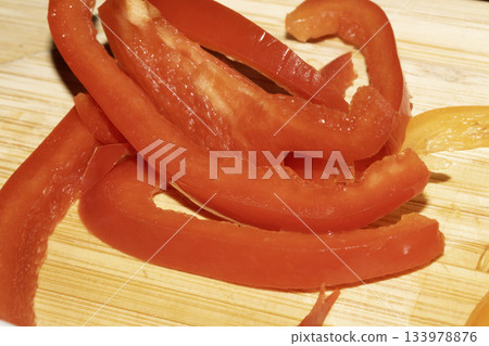 Close up of chopped sliced sweet pepper on a wooden chopping board Close up of chopped sliced sweet pepper on a wooden chopping board 133978876