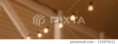 Banner warm string lights hanging under wooden ceiling with copy space 133979222