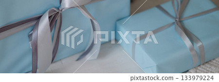 Banner blue gift boxes with silver ribbons on light wooden floor Banner blue gift boxes with silver ribbons on light wooden floor 133979224