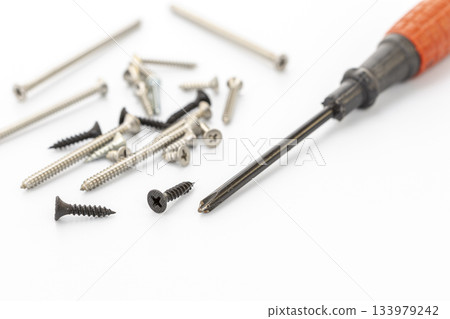 Assorted Screws and Screwdriver on a White Background for DIY Projects 133979242