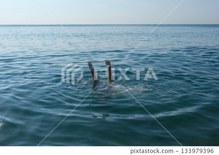 The feet of a drowning child sticking out of the water 133979396