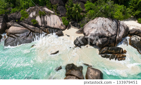 Granite rocks with waves hitting the shoreline on a tropical beach with turquoise waters. Seychelles, Mahe. Roche Copra. 133979451