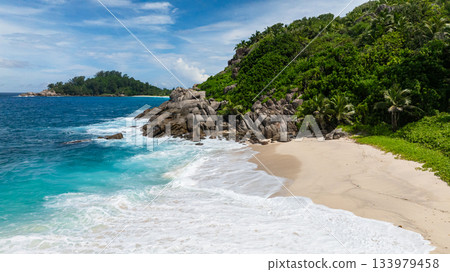 Clear blue water meets dense green foliage along a tropical coastline with sandy shore. Anse Boileau. Seychelles, Mahe. Clear blue water meets dense green foliage along a tropical coastline with sandy shore. Anse Boileau. Seychelles, Mahe. 133979458