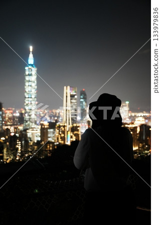 一位女士與台北101的夜景。以璀璨的城市夜景為背景,拍攝了一張美麗的旅行肖像照。 一位女士與台北101的夜景。以璀璨的城市夜景為背景,拍攝了一張美麗的旅行肖像照。 133979836
