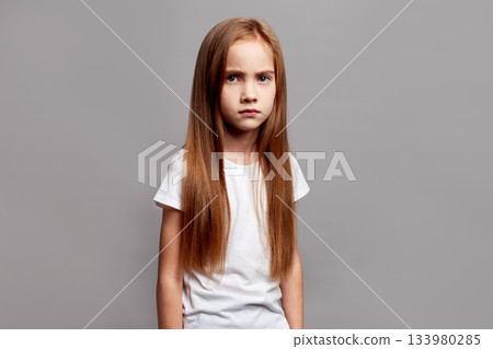 Studio portrait unhappy girl with long hair isolated on neutral background, upset child looking into camera with sad eyes Studio portrait unhappy girl with long hair isolated on neutral background, upset child looking into camera with sad eyes 133980285