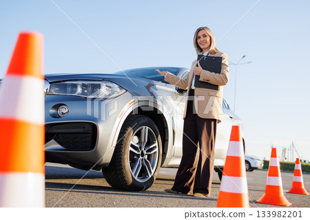 Instructor Presenting Training Car for Driving Lesson Instructor Presenting Training Car for Driving Lesson 133982201