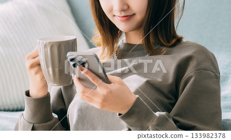 一個女人在客廳裡使用智能手機 一個女人在客廳裡使用智能手機 133982378