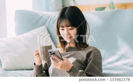 A woman using a smartphone in the living room A woman using a smartphone in the living room 133982379