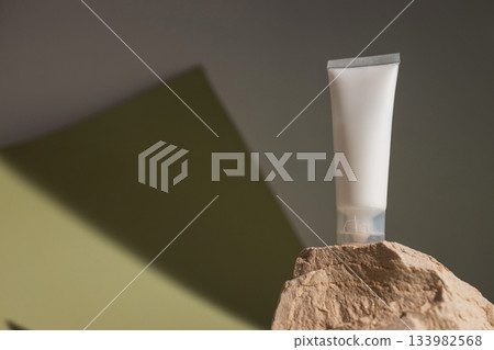 Minimal beauty product mockup with blank cosmetic tube standing on natural stone, styled with warm light and earthy tones for organic skincare, modern branding and clean cosmetic packaging design. 133982568