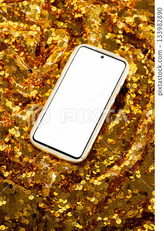 Smartphone with blank white screen on background of shiny golden fabric with sequins Smartphone with blank white screen on background of shiny golden fabric with sequins 133982890