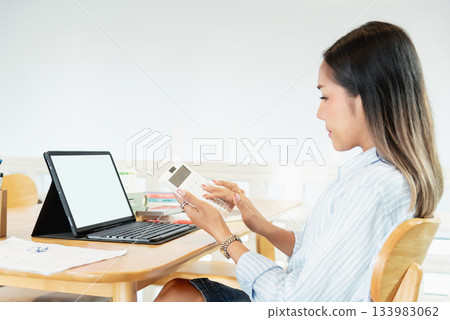 Professional woman calculating finance using calculator and tablet Professional woman calculating finance using calculator and tablet 133983062