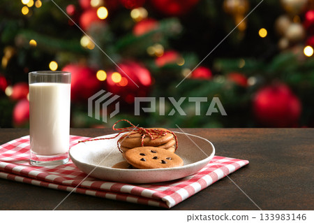 Christmas traditional cookies and milk for Santa Claus in glass near Xmas tree. Copy space. Xmas holiday spirit. Christmas traditional cookies and milk for Santa Claus in glass near Xmas tree. Copy space. Xmas holiday spirit. 133983146