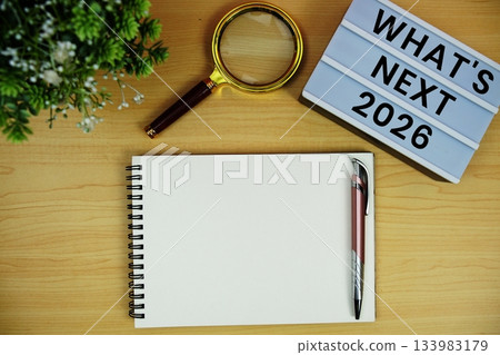 2026 What's Next? text with notepad and magnifying glass on wooden background 2026 What's Next? text with notepad and magnifying glass on wooden background 133983179