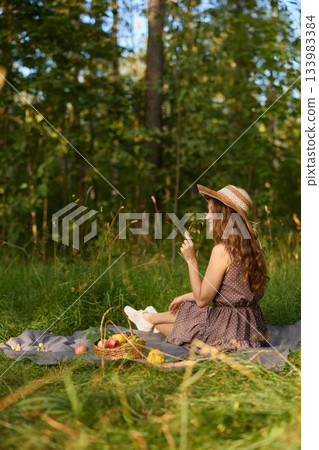 Cheerful young woman enjoys sunshine holding fruit outside 133983384