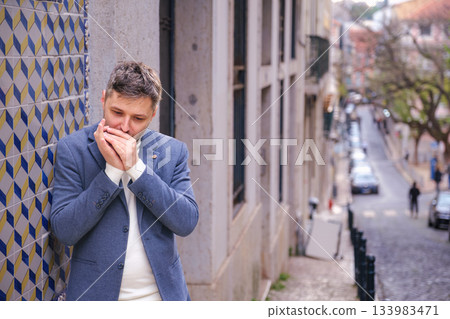Man plays harmonica outdoors in city street 133983471