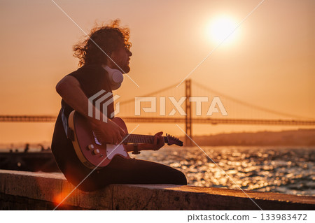 Street musician playing electric guitar in the street 133983472