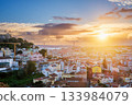 Breathtaking sunset over Lisbon, highlighting the city's rooftops, Carmo Convent ruins, and the iconic 25th of April Bridge. Portugal 133984079