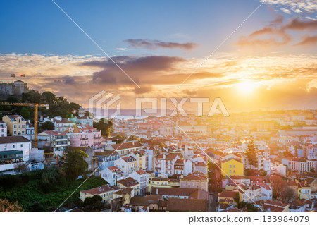 Breathtaking sunset over Lisbon, highlighting the city's rooftops, Carmo Convent ruins, and the iconic 25th of April Bridge. Portugal 133984079