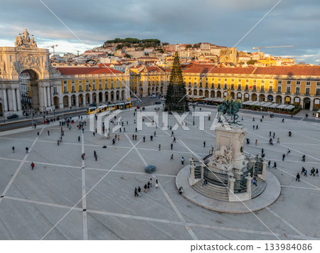The scenic Praca do Comercio in Lisbon showcases a Christmas tree against the sunset sky, highlighting festive winter charm in the evening. Lisbon, Portugal 133984086