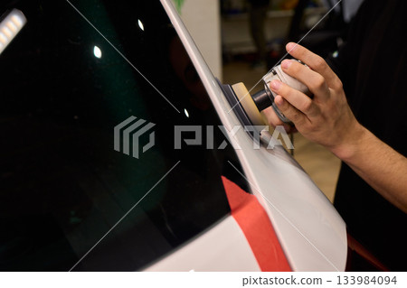 Polishing black car surface thoroughly, Detailed buffing to achieve showroom quality shine, Expert technician uses orbital buffer and foam pad to enhance vehicle gloss Polishing black car surface thoroughly, Detailed buffing to achieve showroom quality shine, Expert technician uses orbital buffer and foam pad to enhance vehicle gloss 133984094