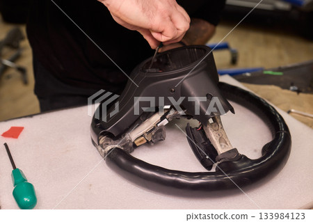 Leather wheel restoration, Repair technician fixing antique leather steering wheel, Expert restoring aged leather steering wheel focusing on stitching and surface details 133984123