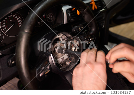 Detailed car repair, Focused shot of hands restoring vehicle steering component carefully, Precision work on vehicle steering wheel with tools in gritty garage environment Detailed car repair, Focused shot of hands restoring vehicle steering component carefully, Precision work on vehicle steering wheel with tools in gritty garage environment 133984127