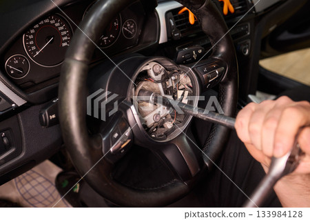 Detailed car repair, Focused shot of hands restoring vehicle steering component carefully, Precision work on vehicle steering wheel with tools in gritty garage environment Detailed car repair, Focused shot of hands restoring vehicle steering component carefully, Precision work on vehicle steering wheel with tools in gritty garage environment 133984128
