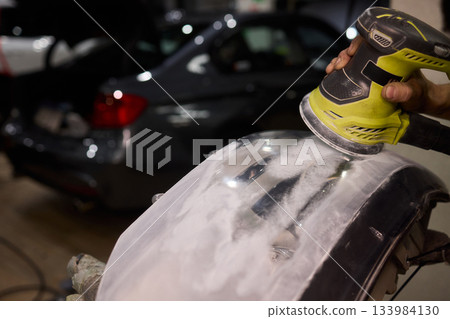 Hands refining car lamps professionally, Orbital buffer restoring clarity to headlights, Closeup of technician smoothing car headlight with orbital buffer and polishing tools Hands refining car lamps professionally, Orbital buffer restoring clarity to headlights, Closeup of technician smoothing car headlight with orbital buffer and polishing tools 133984130