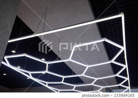 Sleek hexagonal fixtures enhancing modern office and retail environments, Innovative ceiling lighting with geometric shapes to elevate commercial interior aesthetics Sleek hexagonal fixtures enhancing modern office and retail environments, Innovative ceiling lighting with geometric shapes to elevate commercial interior aesthetics 133984165