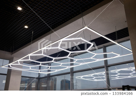 Sleek hexagonal fixtures enhancing modern office and retail environments, Innovative ceiling lighting with geometric shapes to elevate commercial interior aesthetics 133984166