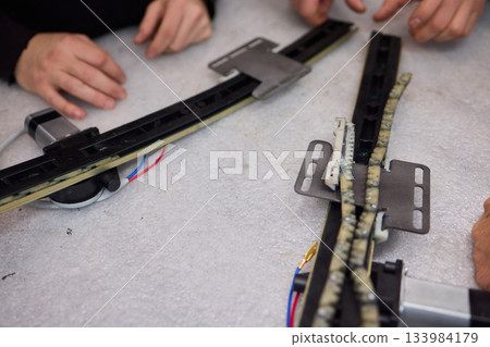 Focused technician conducts precise motor repairs, Dedicated technician methodically finetunes small motor assembly with specialized tools in workshop environment Focused technician conducts precise motor repairs, Dedicated technician methodically finetunes small motor assembly with specialized tools in workshop environment 133984179