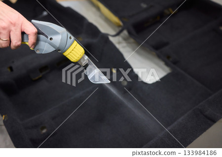 Automotive cleaning process, Professional vehicle upholstery maintenance and dirt removal, Detailed view of cleaning device removing grime from dark fabric upholstery 133984186