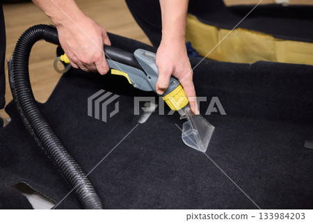 Automotive cleaning process, Professional vehicle upholstery maintenance and dirt removal, Detailed view of cleaning device removing grime from dark fabric upholstery Automotive cleaning process, Professional vehicle upholstery maintenance and dirt removal, Detailed view of cleaning device removing grime from dark fabric upholstery 133984203