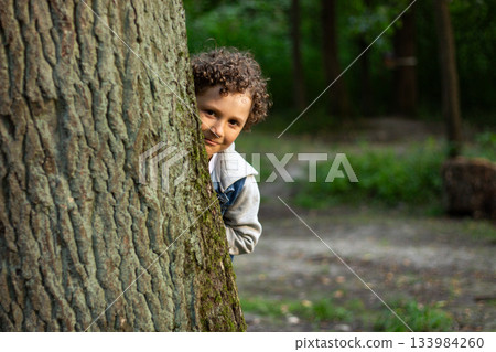 Inquisitive boy exploring something in public park. Park setting and boy wonder are perfect for themes of adventure and exploration. High quality photo. Inquisitive boy exploring something in public park. Park setting and boy wonder are perfect for themes of adventure and exploration. High quality photo. 133984260