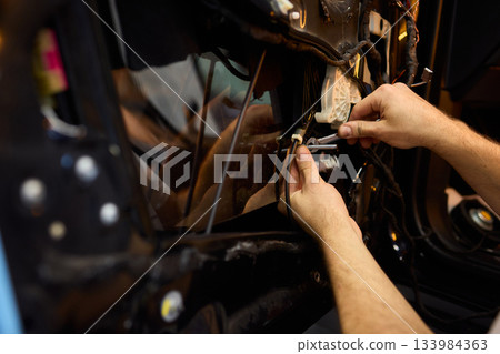 Mechanic fixing vehicle door parts, Closeup of technician repairing car interior components, Professional worker servicing vehicle door with detailed focus and tools Mechanic fixing vehicle door parts, Closeup of technician repairing car interior components, Professional worker servicing vehicle door with detailed focus and tools 133984363
