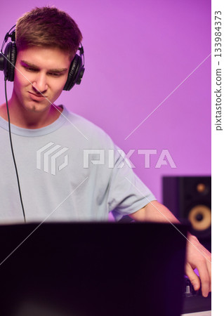 Youthful technician editing sound, Youthful sound engineer meticulously adjusting mixing console within modern streaming design setting to create perfect audio balance Youthful technician editing sound, Youthful sound engineer meticulously adjusting mixing console within modern streaming design setting to create perfect audio balance 133984373