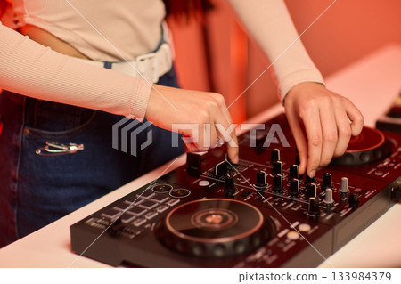 DJ setup overview, Energetic club DJ performing with digital controller in action, Content creator mixing music live using digital turntables under vibrant stage lights DJ setup overview, Energetic club DJ performing with digital controller in action, Content creator mixing music live using digital turntables under vibrant stage lights 133984379