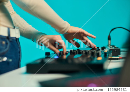 DJ setup overview, Energetic club DJ performing with digital controller in action, Content creator mixing music live using digital turntables under vibrant stage lights 133984381
